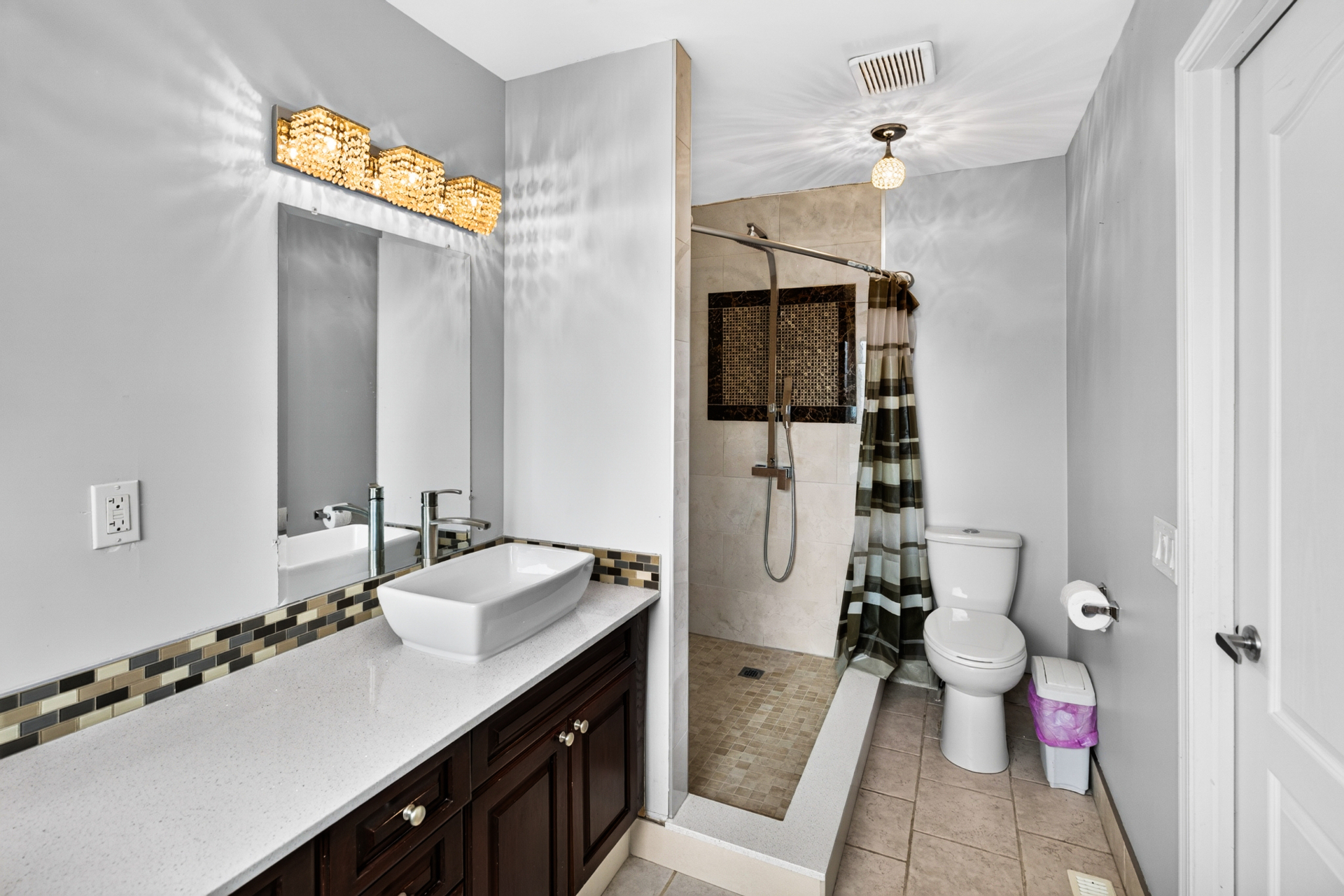 Updated bathroom with vessel sink, mosaic tile accent, and walk-in tiled shower