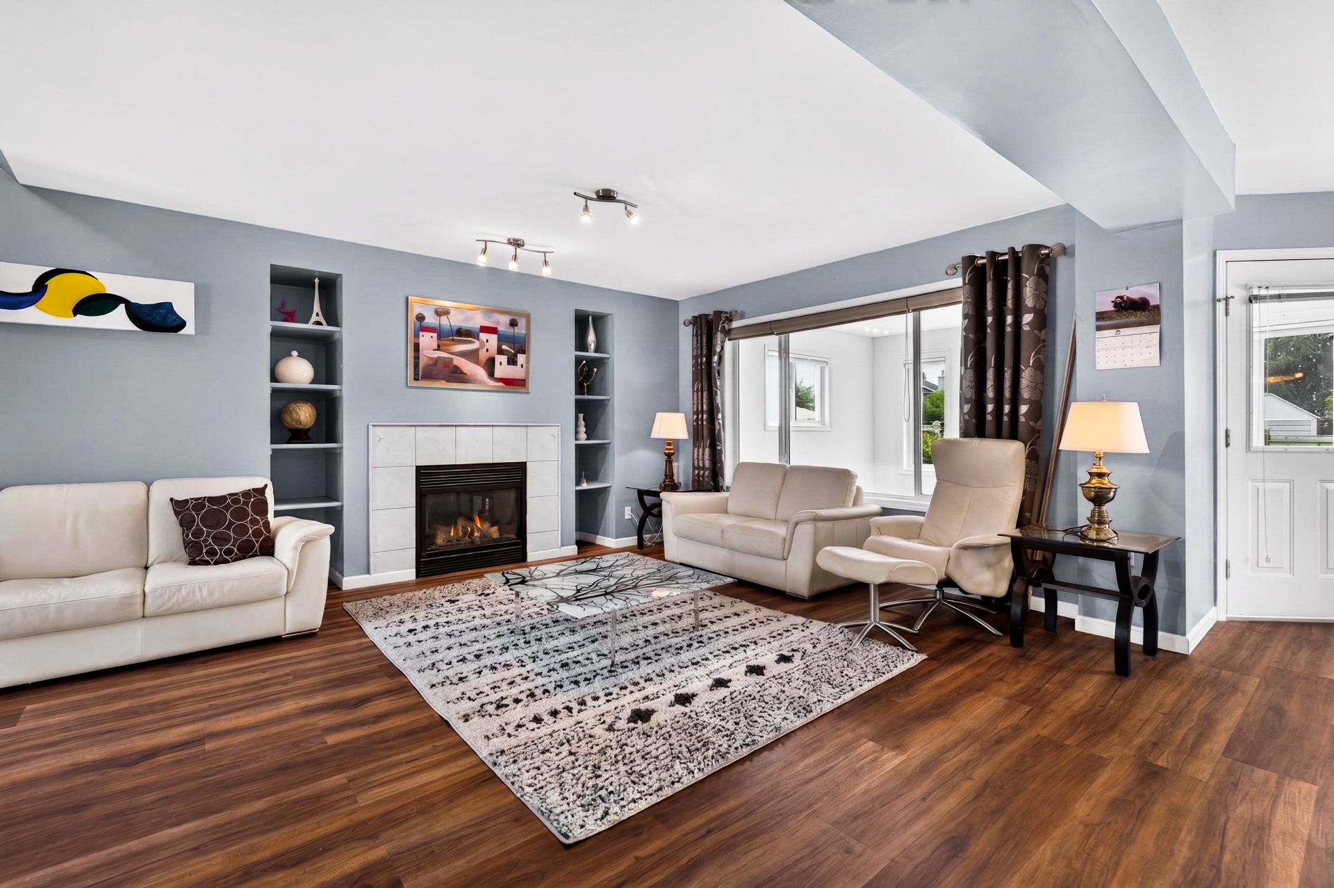 Main living room with tile-surround gas fireplace, built-in shelving, and large picture window